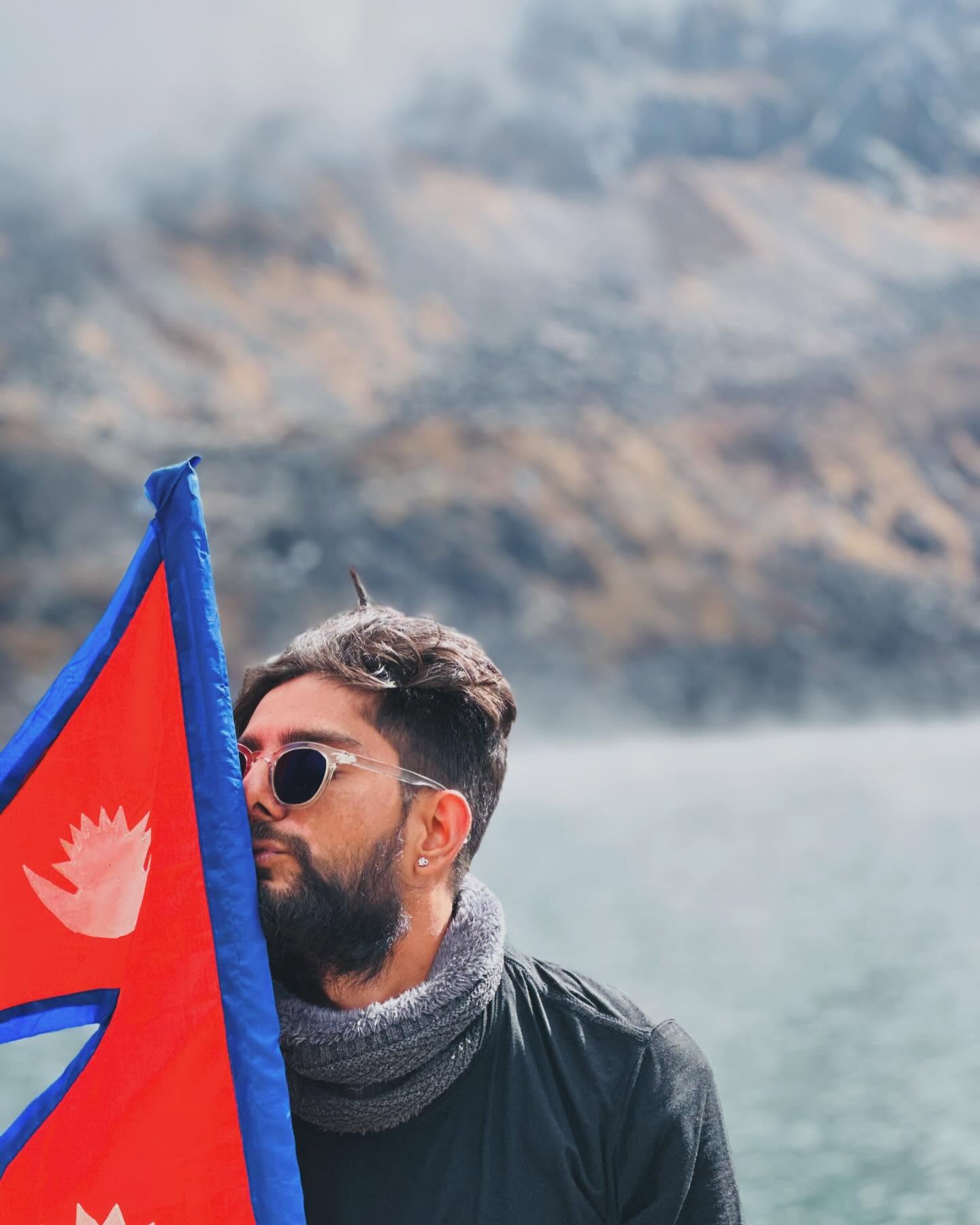 The founder of Reet Trails holding the Nepal flag to his face on a misty trail